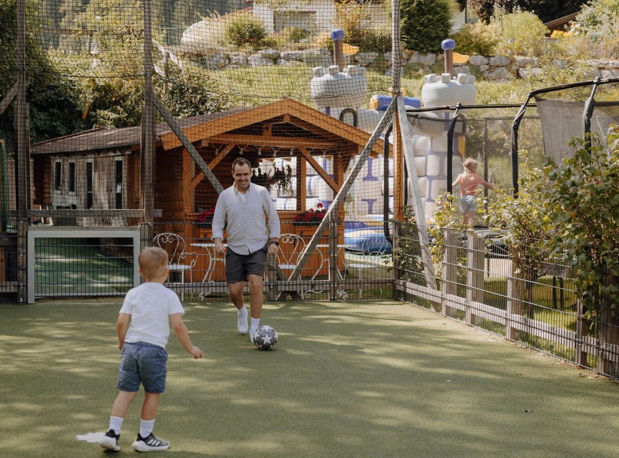 Vater und Kind beim gemeinsamen Fußballspielen auf dem Hotelspielplatz